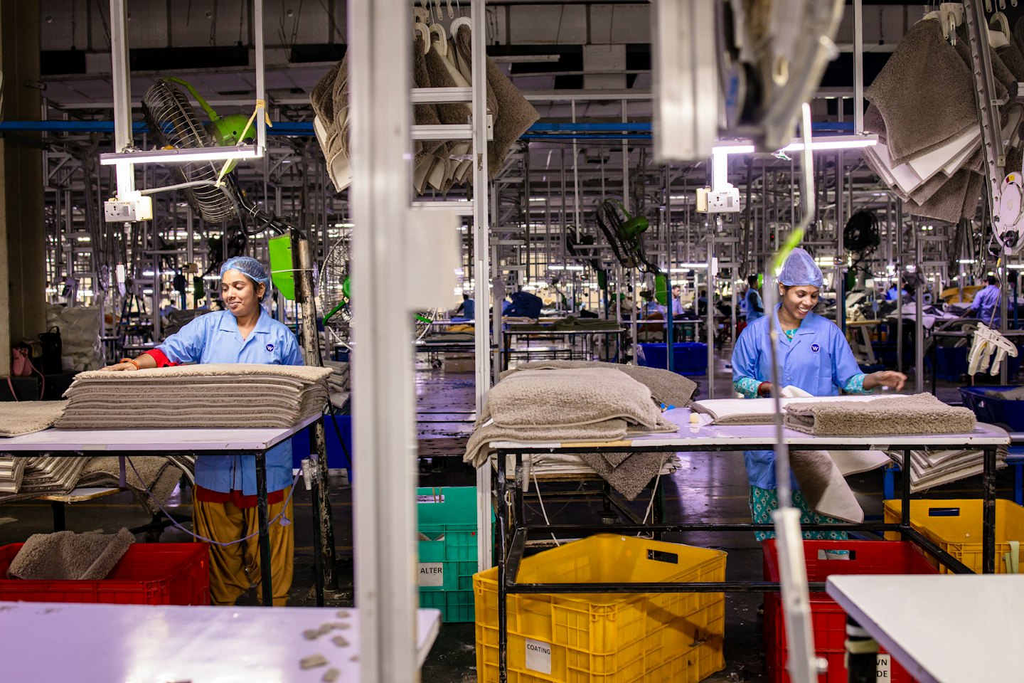 Two women in blue uniforms sort textiles in a factory.